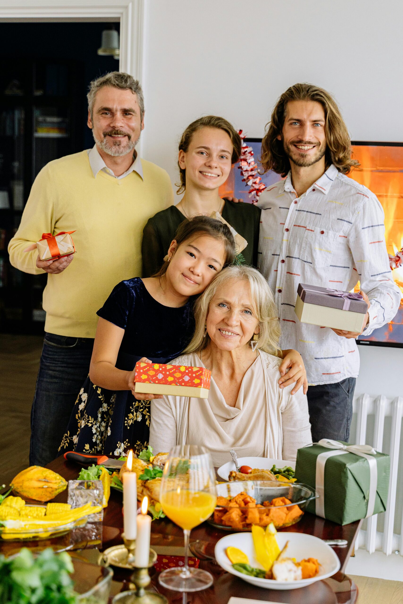 Three generations of a family enjoying a festive celebration with gifts and a meal.