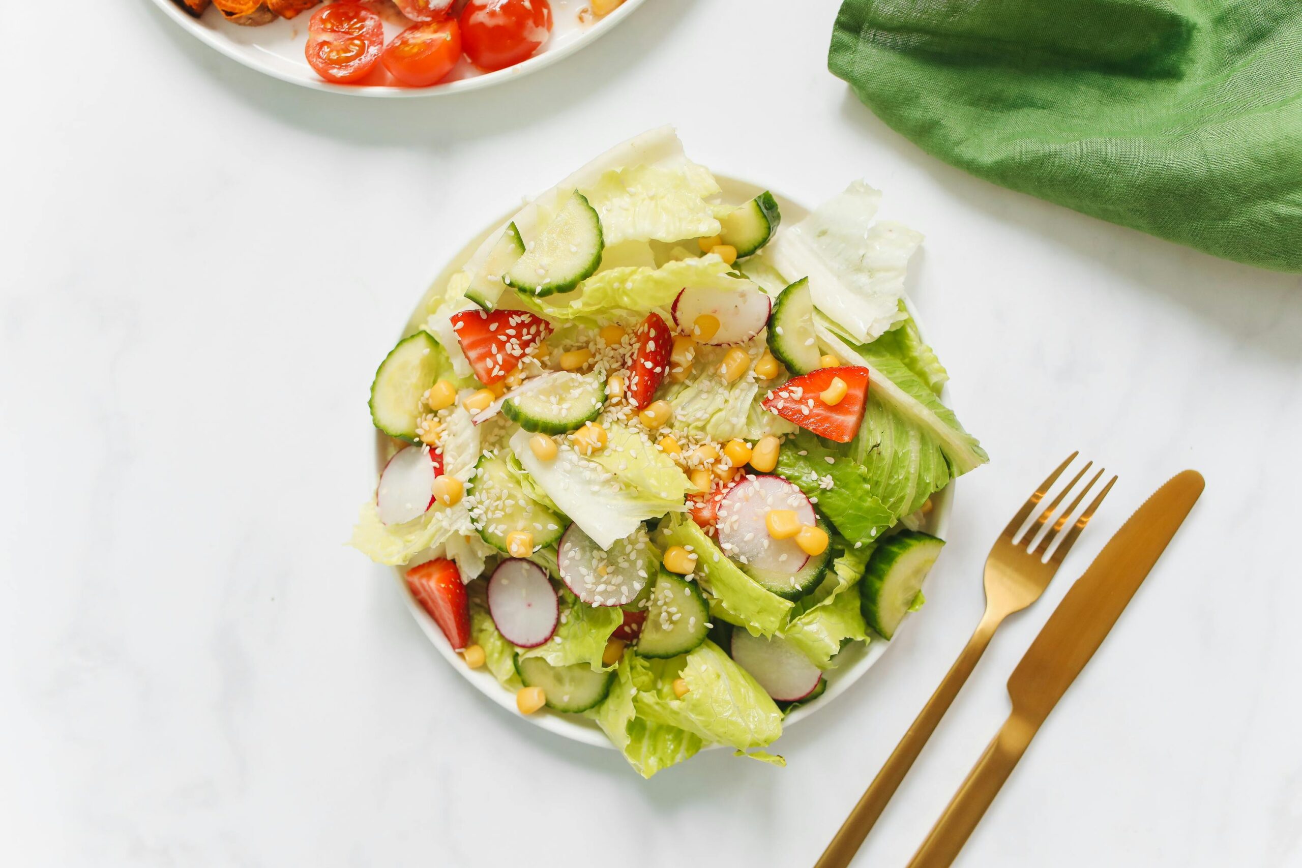 2 Colorful vegetable salad with lettuce, cucumbers, and radishes on a white plate.